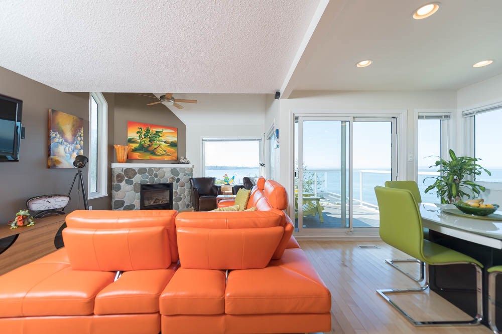 White Rock — existing living room with orange sectional and stone fireplace before renovation