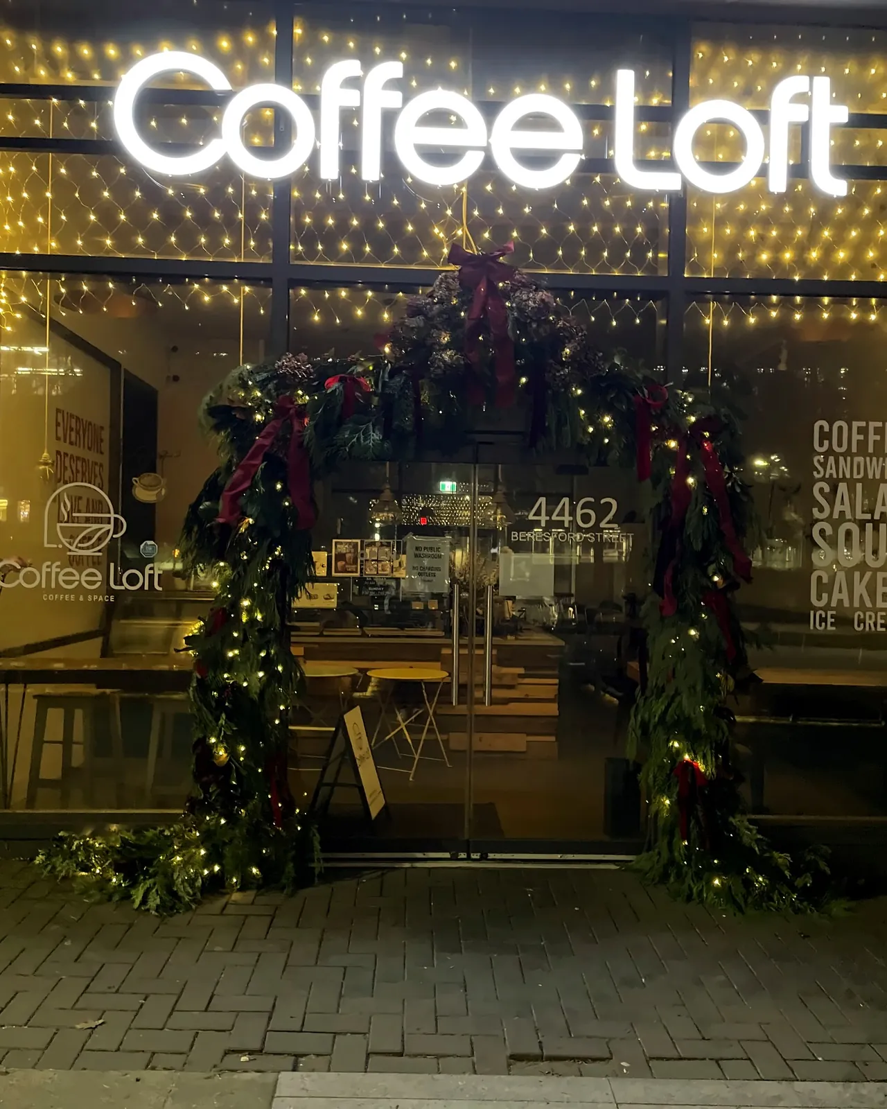 The Coffee Loft Christmas archway lit with warm white lights at night
